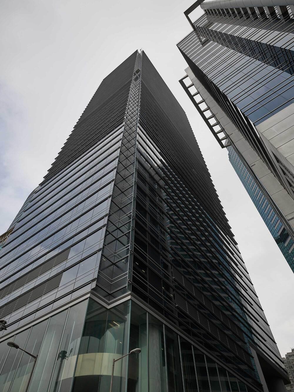 Upward view of a modern glass skyscraper on a cloudy day